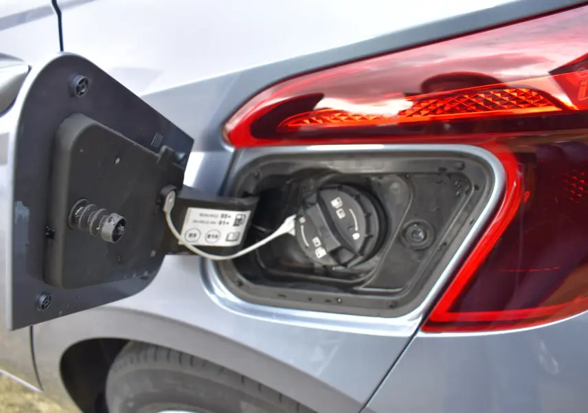 Gros plan sur l'ouverture de la trappe à carburant côté gauche d'une Hyundai i20 bleu clair avec feu arrière rouge.
