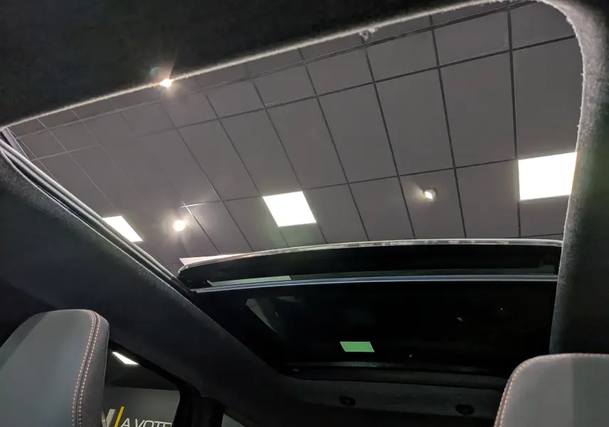 Toit ouvrant panoramique vu de l'intérieur du Dacia Bigster 2026, avec ciel de toit noir et sièges tissu gris.