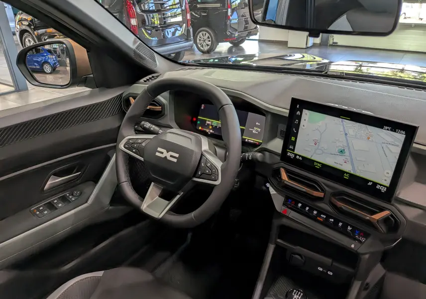Vue intérieure côté conducteur du Dacia Bigster 2026, tableau de bord noir avec écran tactile et volant multifonction.
