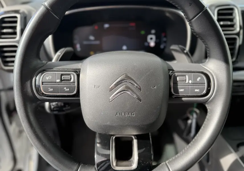 Vue rapprochée du volant noir de la Citroën C5 Aircross 2021 avec commandes intégrées et logo chromé central.