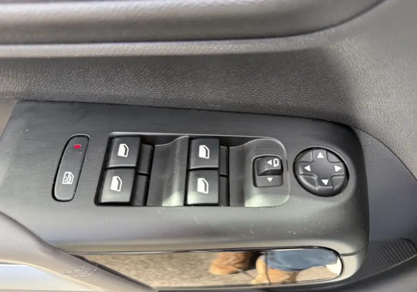 Gros plan sur les commandes des vitres électriques et des rétroviseurs côté conducteur d’un Citroën C5 Aircross blanc.