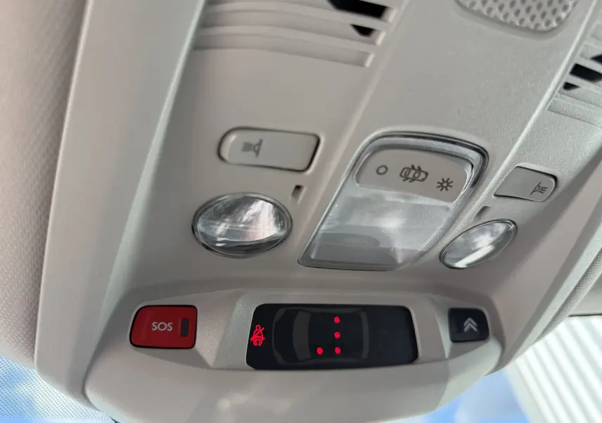 Plafonnier intérieur avec commandes d’éclairage et bouton SOS du Citroën C5 Aircross blanc, vue en léger contre-plongée.