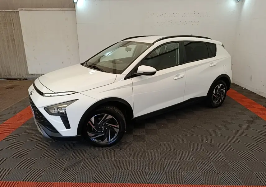 Hyundai Bayon blanc en 3/4 avant droit, avec jantes noires et toit ouvrant visible en intérieur fermé.