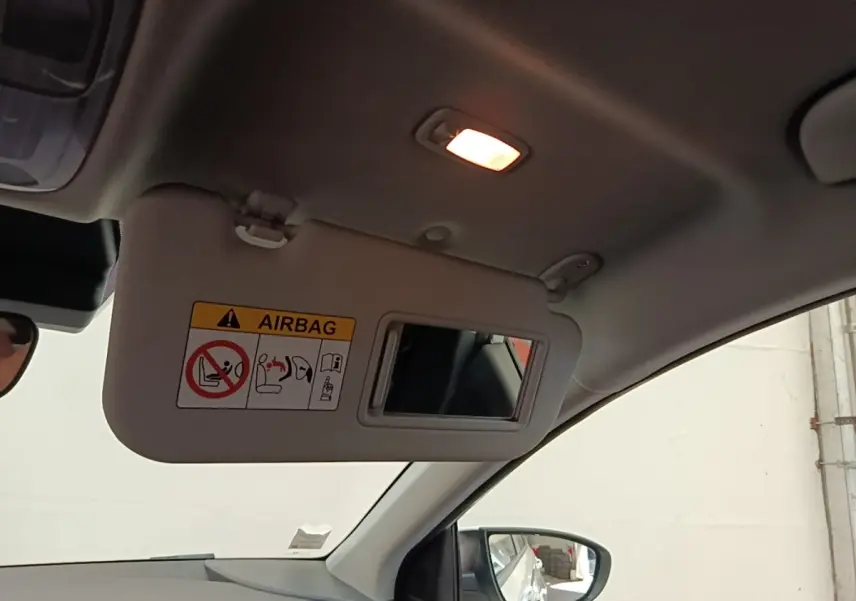 Intérieur du Hyundai Bayon 2024 blanc, vue sur le pare-soleil côté conducteur avec miroir et lumière allumée.