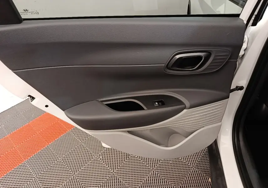 Vue intérieure de la porte arrière droite blanche du Hyundai Bayon 2024 avec garniture bicolore noire et grise.