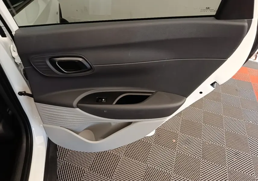 Vue rapprochée de la porte arrière gauche blanche du Hyundai Bayon 2024 avec garniture intérieure noire et grise.