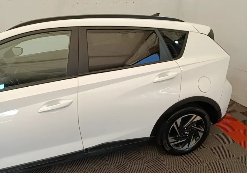 Vue latérale droite d'une Hyundai Bayon blanche, mettant en valeur les jantes noires et le toit noir contrastant.