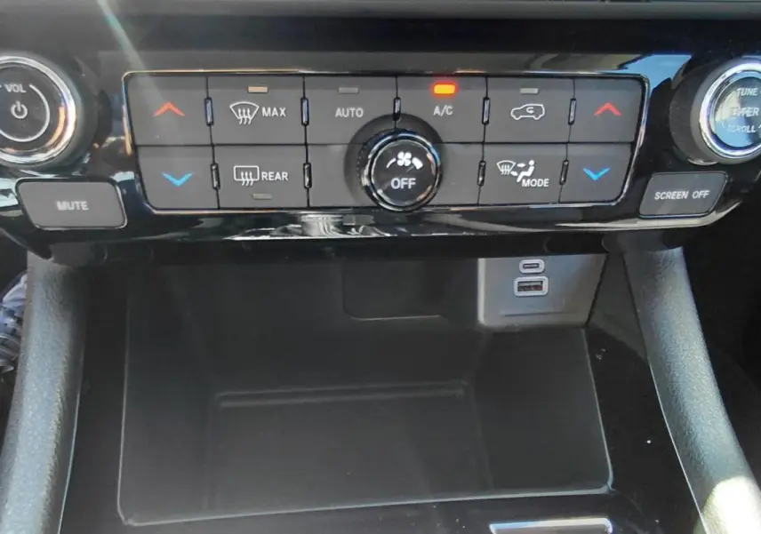 Vue rapprochée de la console centrale du Jeep Compass 2025, avec commandes climatisation et ports USB visibles.