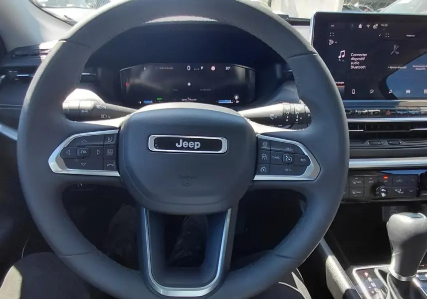Vue intérieure centrée sur le volant Jeep noir et l’écran tactile du tableau de bord du Compass 2025.