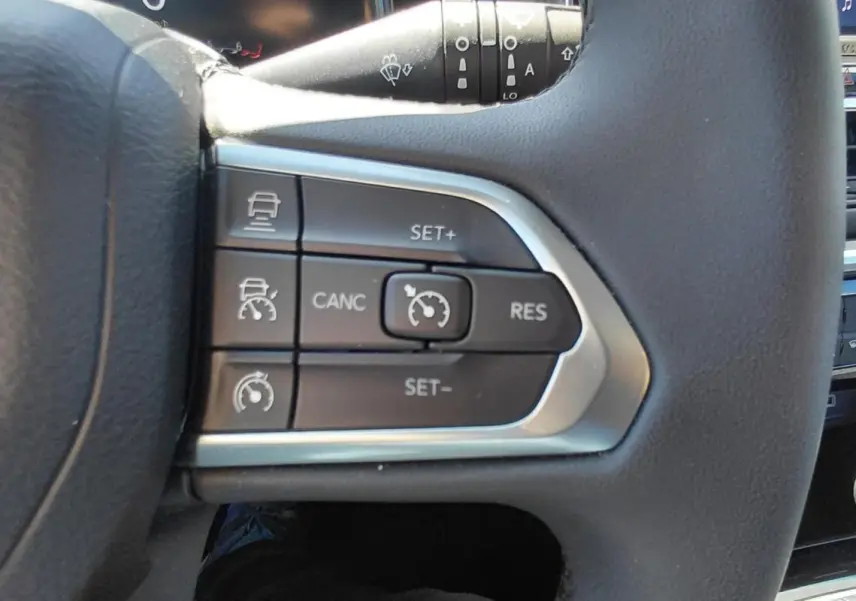 Gros plan sur les commandes du régulateur de vitesse au volant du Jeep Compass bleu 2025 e-Hybrid.
