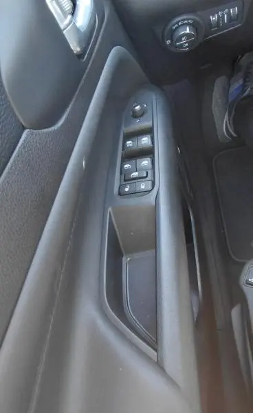 Vue rapprochée de la porte côté gauche du Jeep Compass bleu 2025, montrant les commandes électriques des vitres et des rétroviseurs.