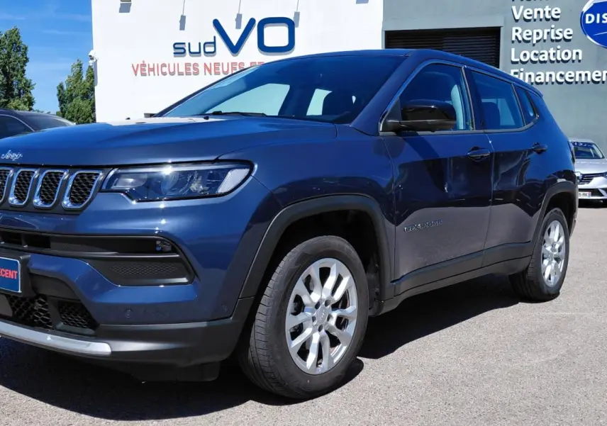 Jeep Compass bleu 3/4 avant droit, jantes alliage 18 pouces, calandre distinctive et phares LED visibles.