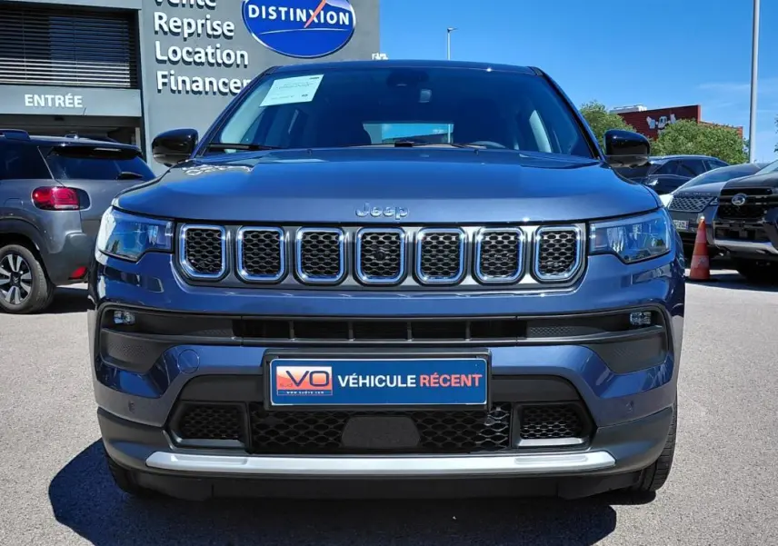 Vue frontale d'un Jeep Compass bleu 2025 avec calandre chromée et plaque "Véhicule récent" visible.