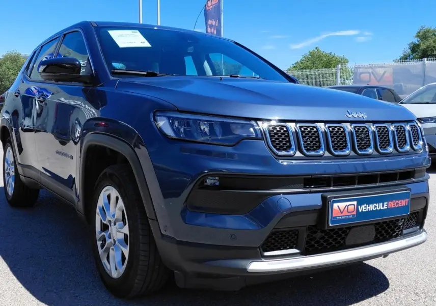 Jeep Compass bleu en 3/4 avant droit, avec calandre distinctive à sept fentes et jantes alliage 18 pouces.