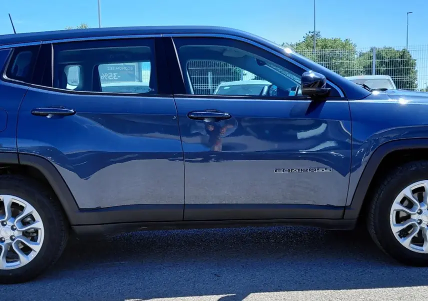 Vue latérale droite d'un Jeep Compass bleu 2025 avec jantes alliage 18 pouces et logo "Compass" sur la porte.