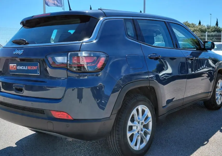 Jeep Compass bleu vue 3/4 arrière droit, avec jantes alliage 18 pouces et feux arrière LED visibles.