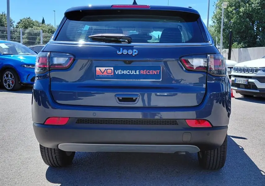 Vue arrière d’un Jeep Compass bleu 2025 avec feux LED et plaque « Véhicule récent » visible au centre.