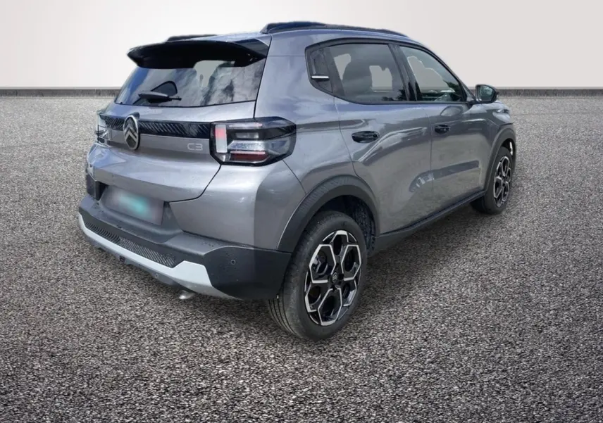 Vue 3/4 arrière droite d'une Citroën C3 hybride 2026 gris foncé avec jantes noires et détails noirs contrastants.