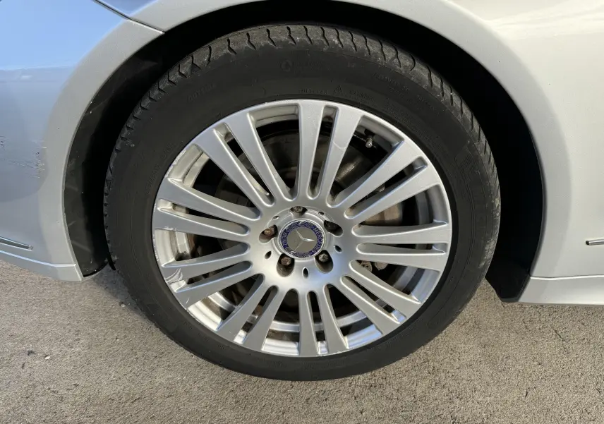 Gros plan sur la jante alliage argentée avec logo Mercedes d'une Mercedes Classe E 250 Coupé gris côté arrière droit.