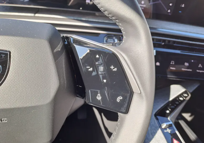 Gros plan sur la commande gauche du volant gris clair du Peugeot 3008 2024 avec boutons de volume et appel.
