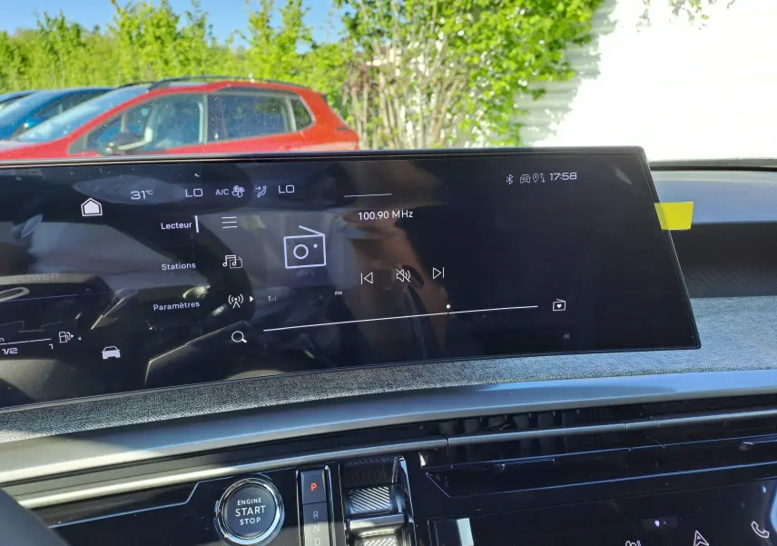 Écran tactile central du tableau de bord du Peugeot 3008 gris Artense, affichant la radio FM à 100.90 MHz en extérieur lumineux.