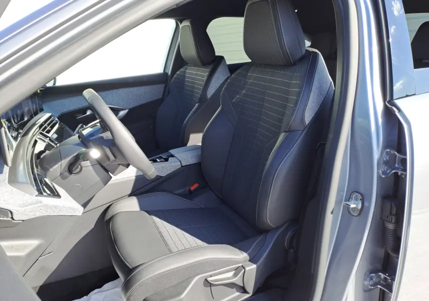 Vue intérieure côté conducteur du Peugeot 3008 gris Artense 2024, sièges tissu et cuir avec coutures contrastées.