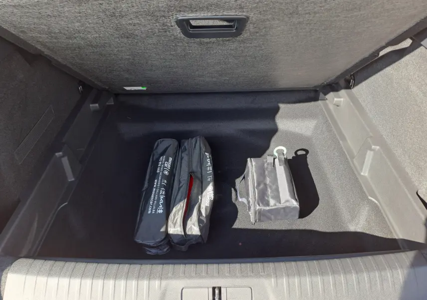 Coffre ouvert du Peugeot 3008 gris Artense, montrant un espace de rangement propre avec trois sacs d'accessoires noirs.