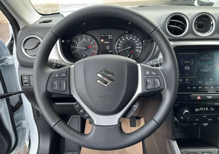 Vue intérieure centrée sur le volant du Suzuki Vitara 2025 blanc nacré avec tableau de bord et écran tactile.