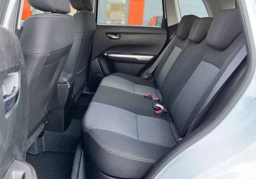 Vue côté droit de l'habitacle arrière du Suzuki Vitara 2025 blanc nacré, sièges tissu bicolore gris et noir.