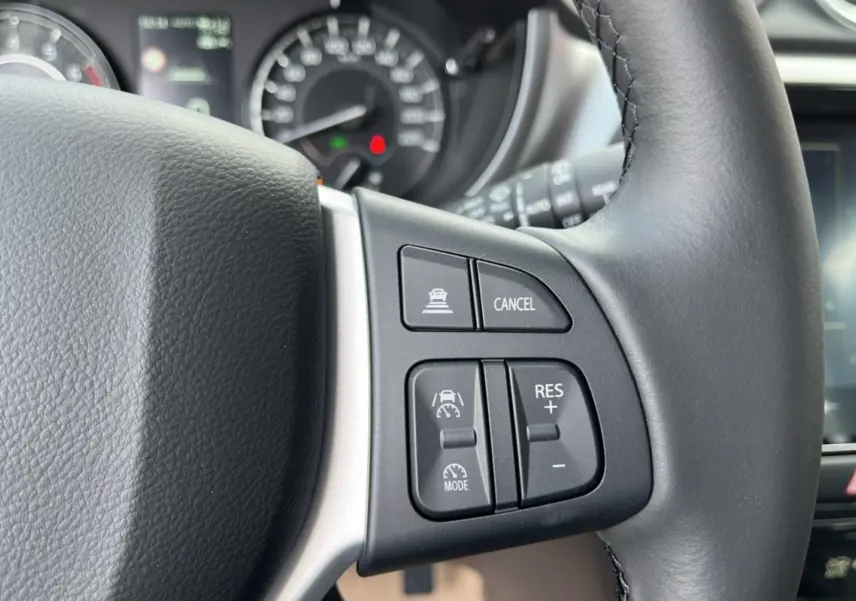 Gros plan sur les commandes au volant du Suzuki Vitara 2025 blanc nacré, avec régulateur de vitesse et fonction cancel.