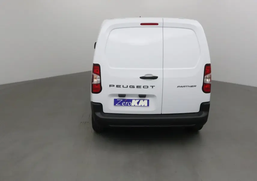 Vue arrière d’un utilitaire Peugeot Partner blanc avec portes battantes et plaque Zero KM visible.