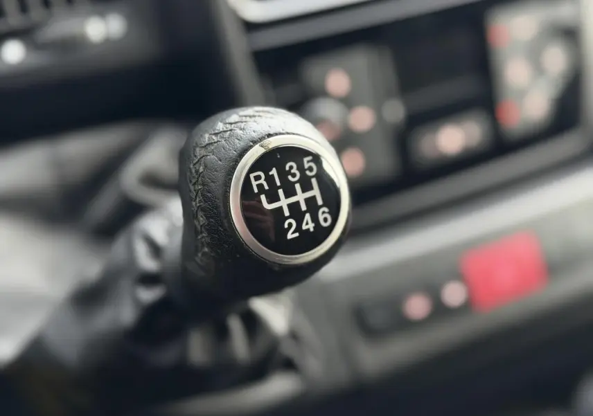 Gros plan sur le pommeau en cuir noir de la boîte manuelle 6 vitesses du fourgon Opel Movano blanc 2024.