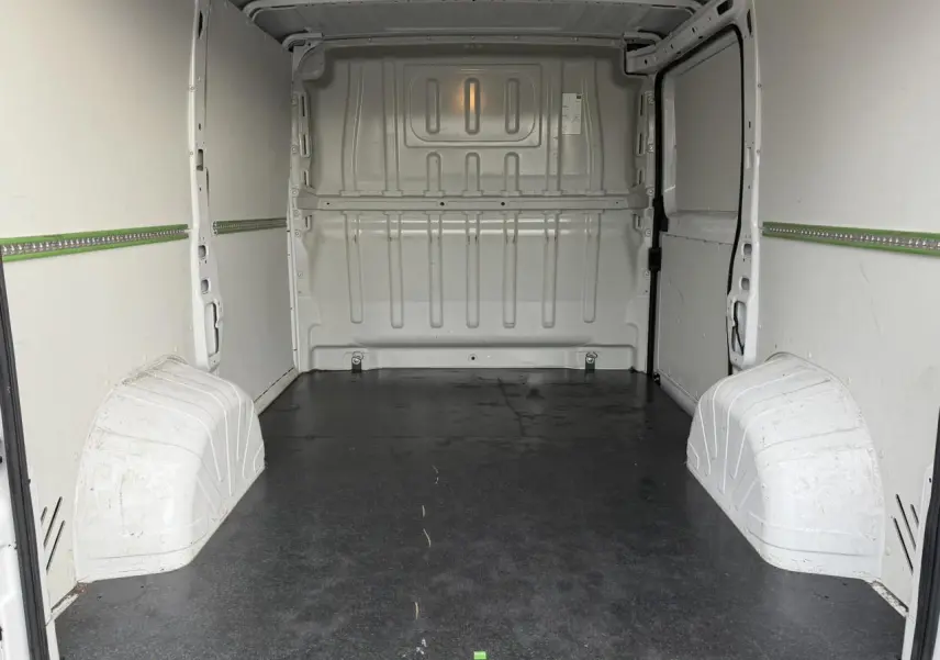 Vue intérieure arrière du fourgon blanc Opel Movano L1H1, montrant l’espace de chargement avec plancher bois noir.