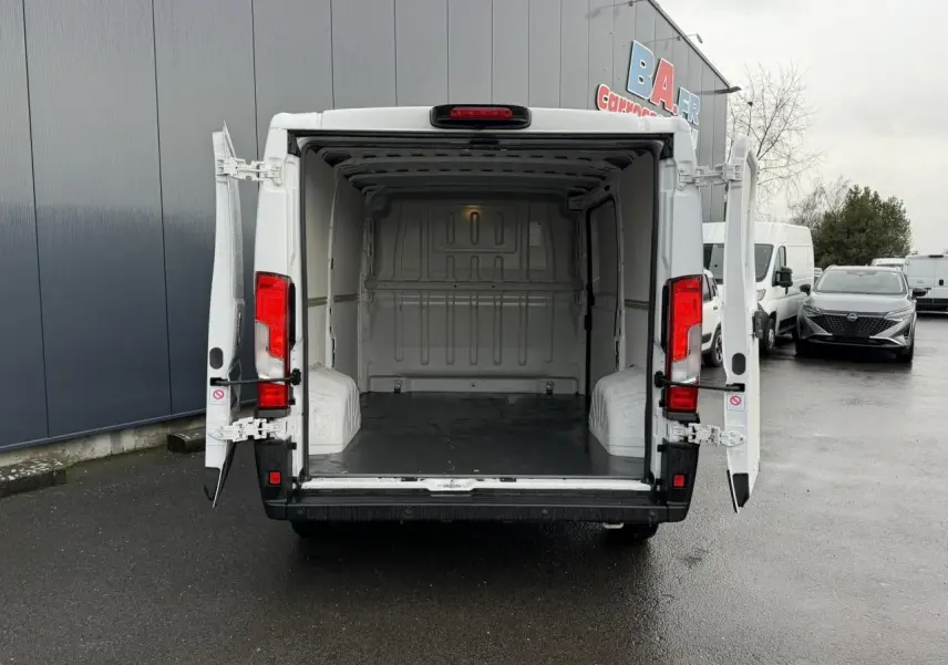 Vue arrière d’un Opel Movano Fourgon blanc 2024 avec portes arrière ouvertes montrant l’espace de chargement vide.