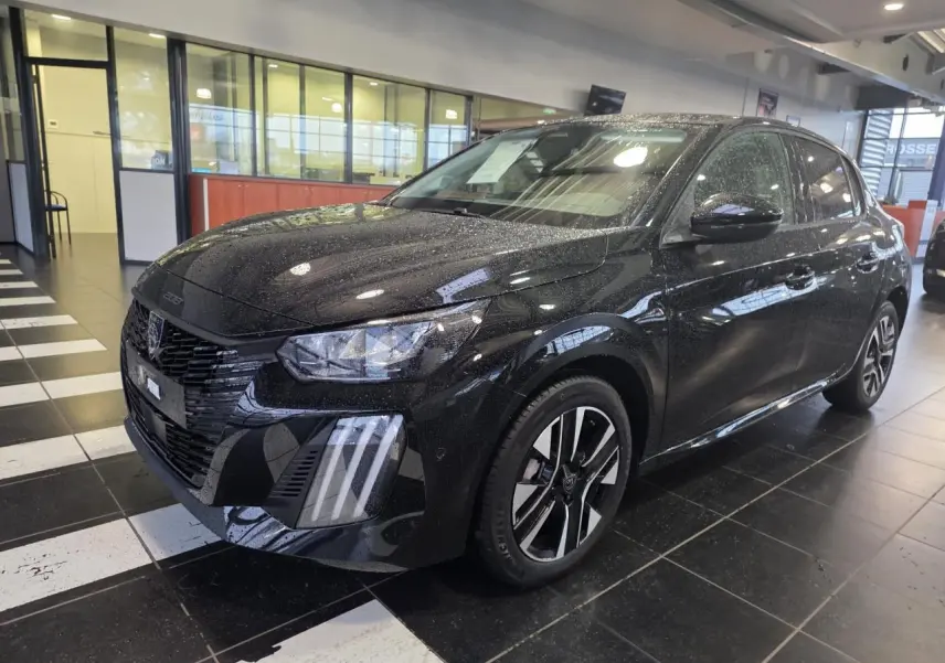 Peugeot 208 hybride noire métallisée vue 3/4 avant droit en intérieur avec jantes alliage bi-tons et feux LED griffés.