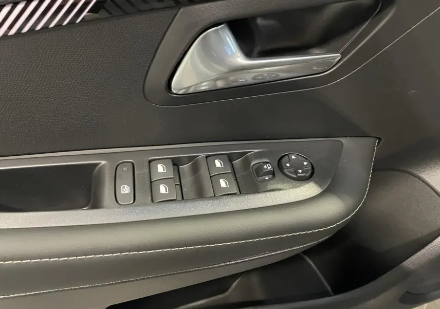 Détail de la porte avant gauche de la Peugeot 208 noire métallisée avec commandes de vitres et rétroviseurs.