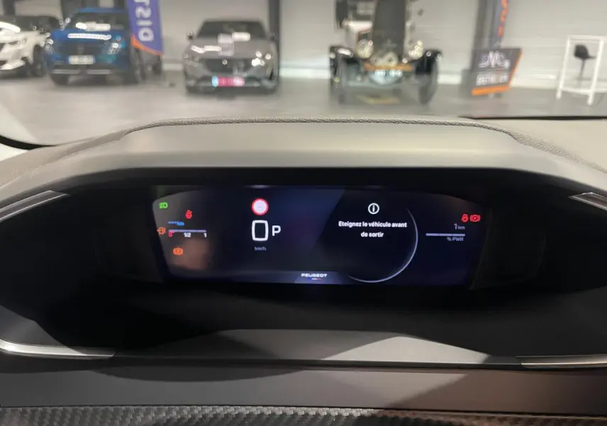 Vue rapprochée du combiné numérique Peugeot 208 1.2i Hybrid 2025 affichant le mode parking et alertes.