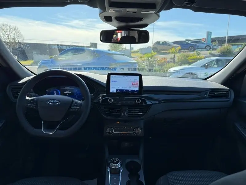Vue intérieure avant du Ford Kuga 2.0 EcoBlue 2024, tableau de bord noir avec écran tactile central et volant cuir multifonction.