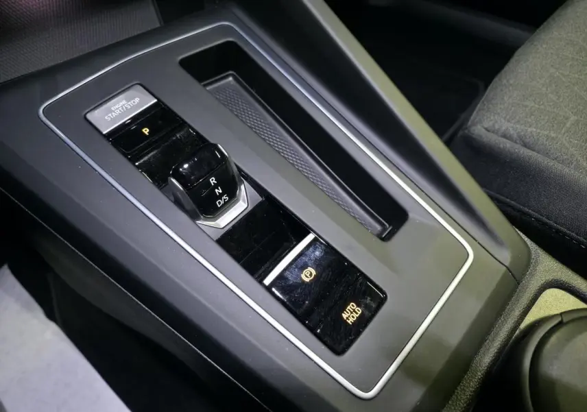 Gros plan sur la console centrale noire de la Volkswagen Golf VIII avec levier de vitesses automatique et bouton start/stop.