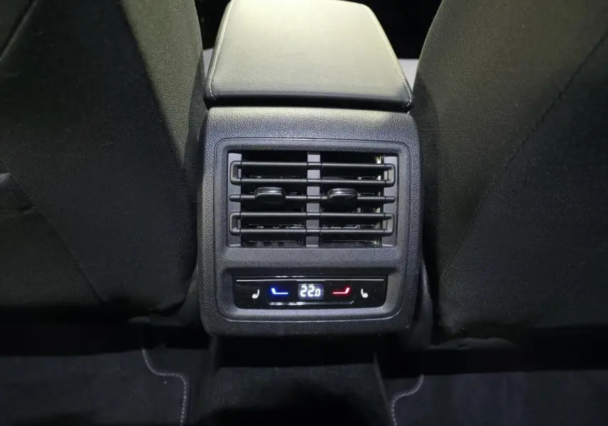 Vue rapprochée de la console arrière avec commandes climatisation et sièges chauffants, intérieur tissu noir de la Volkswagen Golf VIII rouge.