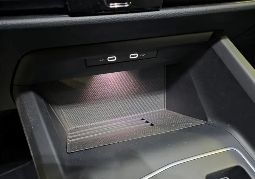 Gros plan sur la console centrale intérieure de la Volkswagen Golf VIII rouge, montrant deux ports USB-C éclairés.