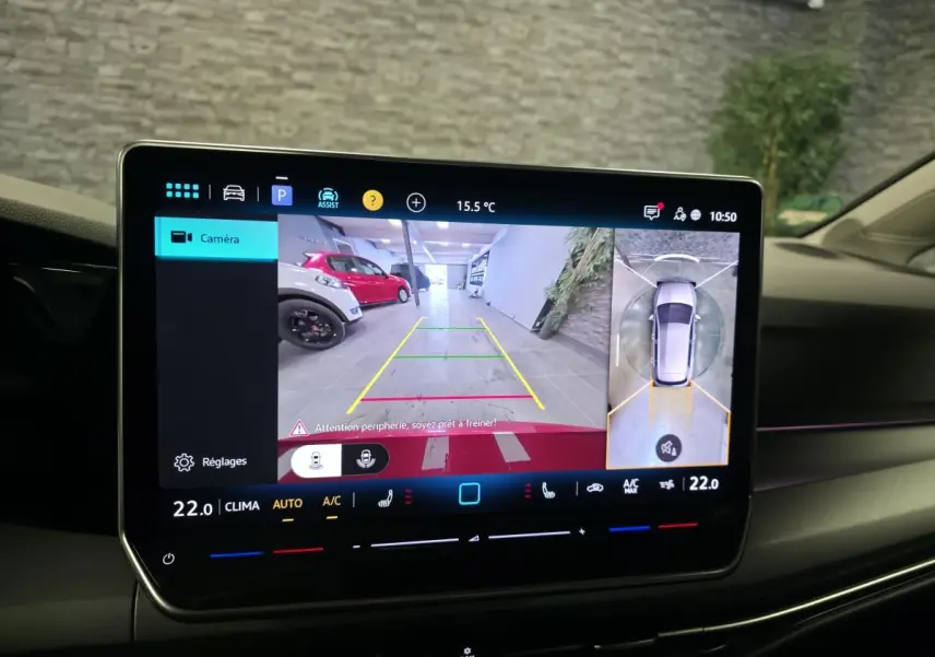 Écran central de la Volkswagen Golf VIII rouge montrant la caméra 360 et la vue arrière en stationnement intérieur.