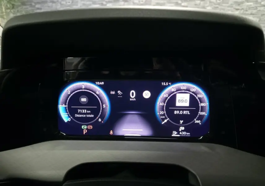 Vue rapprochée du combiné d'instruments digital bleu et noir de la Volkswagen Golf VIII rouge, affichant 7133 km.