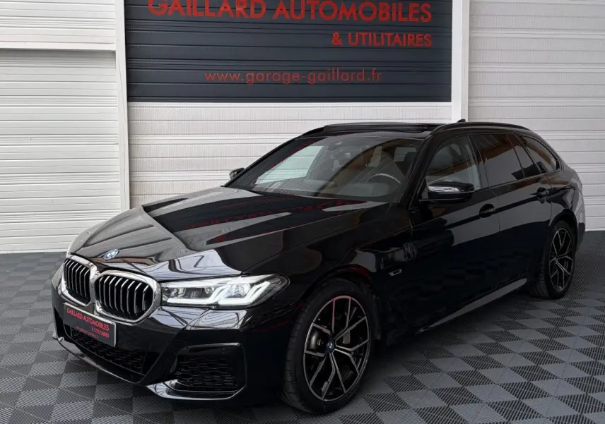 BMW Série 5 Touring 530e noir en 3/4 avant droit, avec jantes M Sport et calandre chromée distinctive.