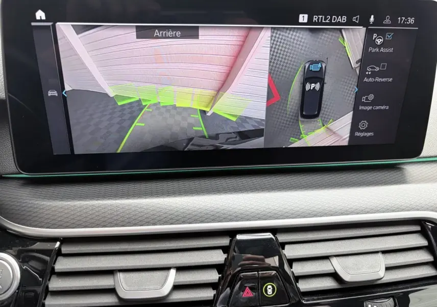 Écran tactile intérieur montrant l’aide au stationnement arrière et vue 3D du BMW Série 5 Touring noir 2023.