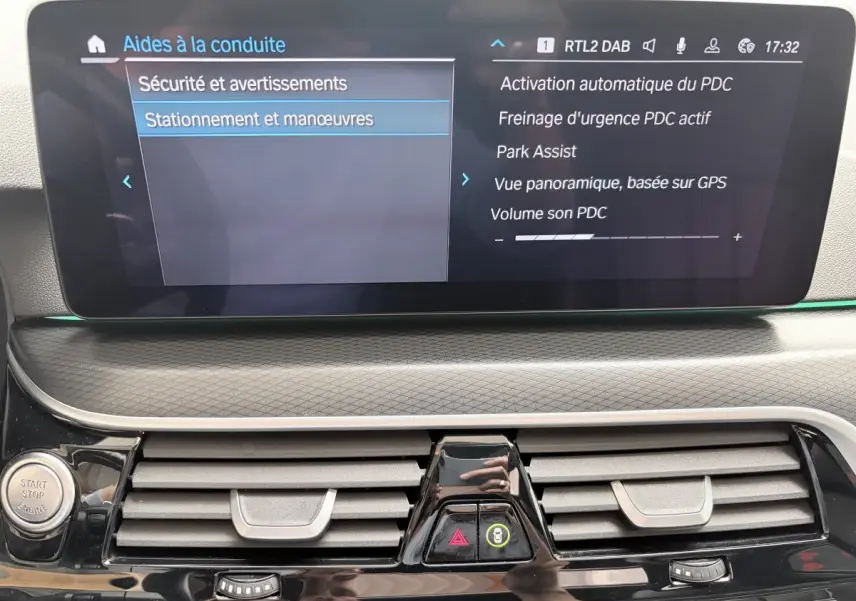 Vue rapprochée du tableau de bord noir de la BMW Série 5 Touring 530e 2023, affichant l'écran tactile des aides au stationnement.
