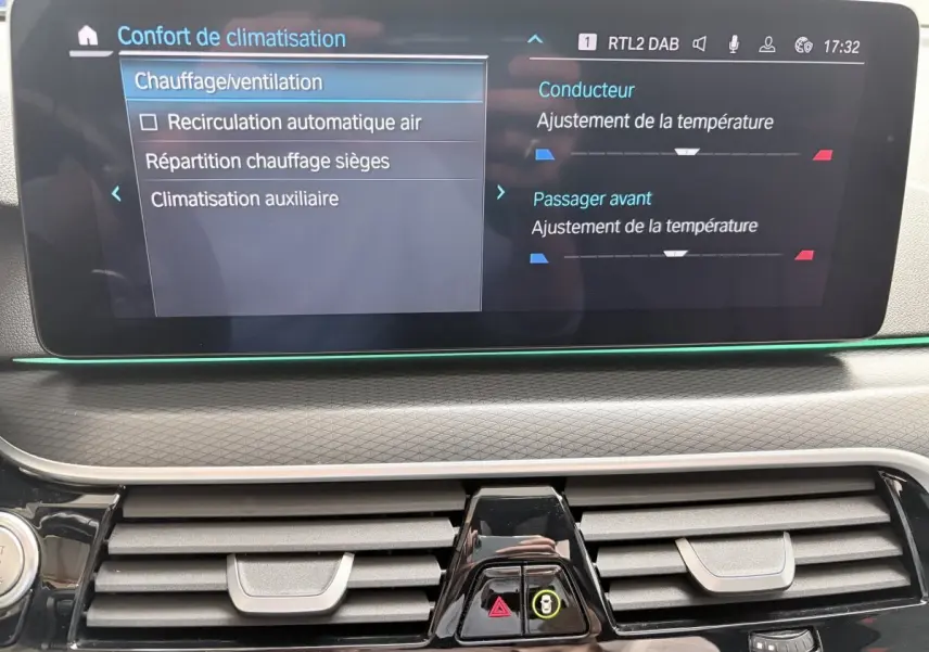 Écran tactile central affichant les réglages de climatisation dans l'habitacle d'une BMW Série 5 Touring noire.