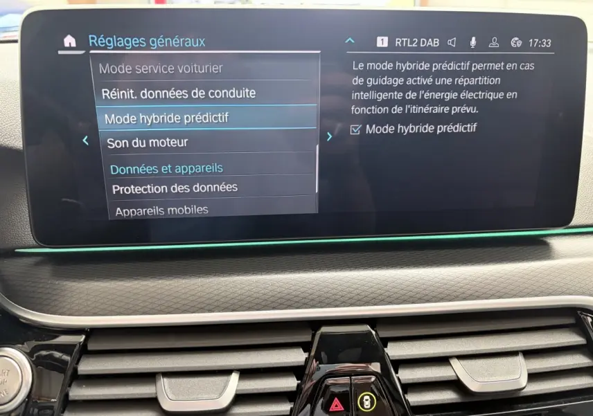Écran tactile central affichant les réglages du mode hybride prédictif dans l'habitacle d'une BMW Série 5 Touring noire.