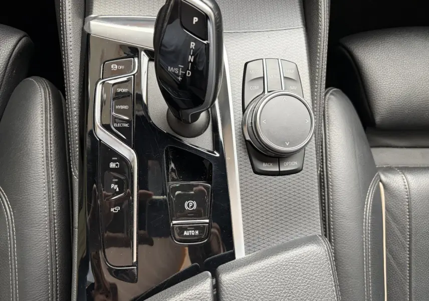 Gros plan sur la console centrale noire de la BMW Série 5 Touring 530e avec levier de vitesses et molette de contrôle.