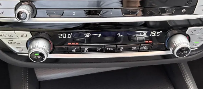 Gros plan sur la console centrale noire de la BMW Série 5 Touring 530e, affichant la climatisation automatique bi-zone.